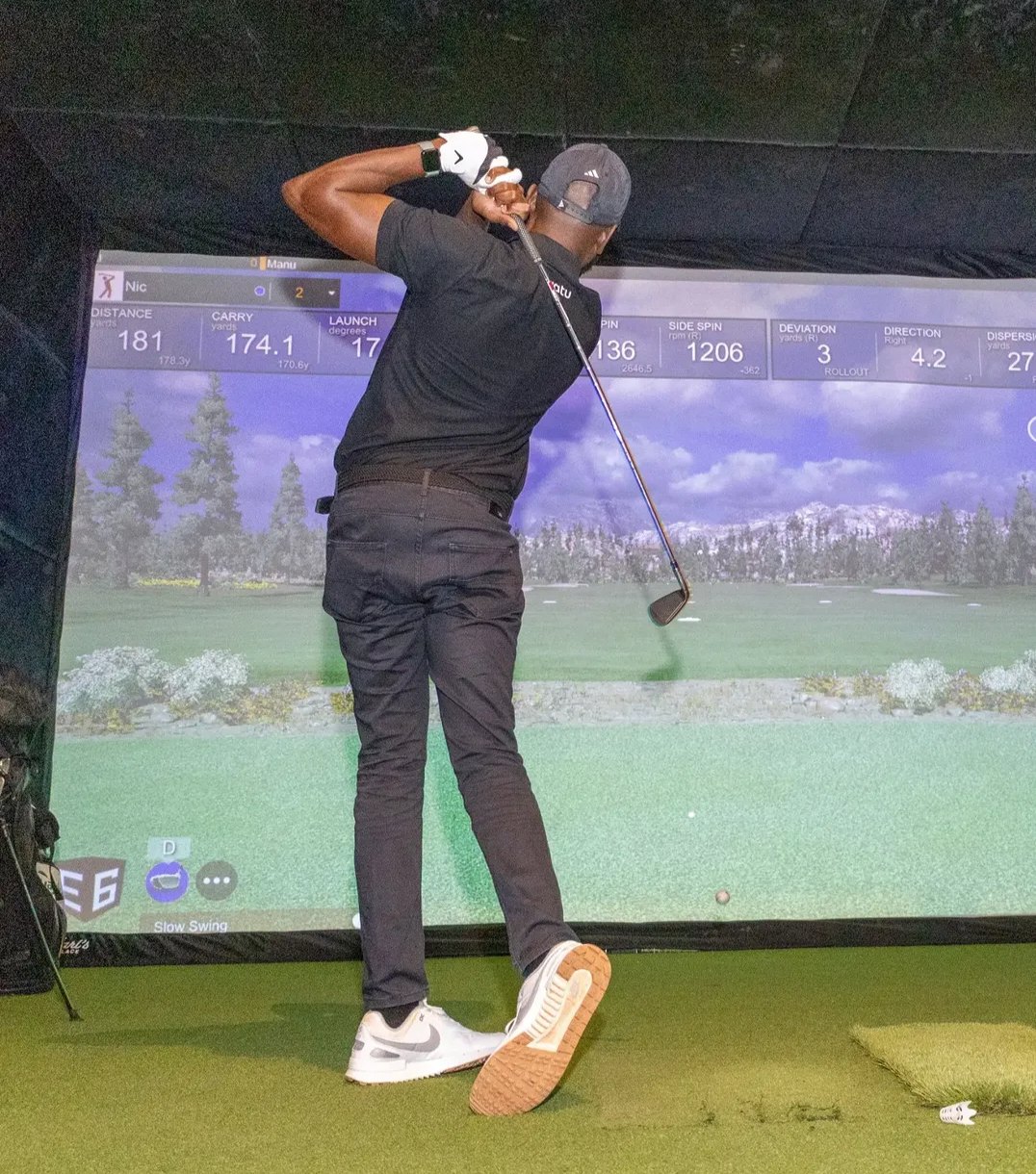 A golfer mid-swing in a Birdies golf bay